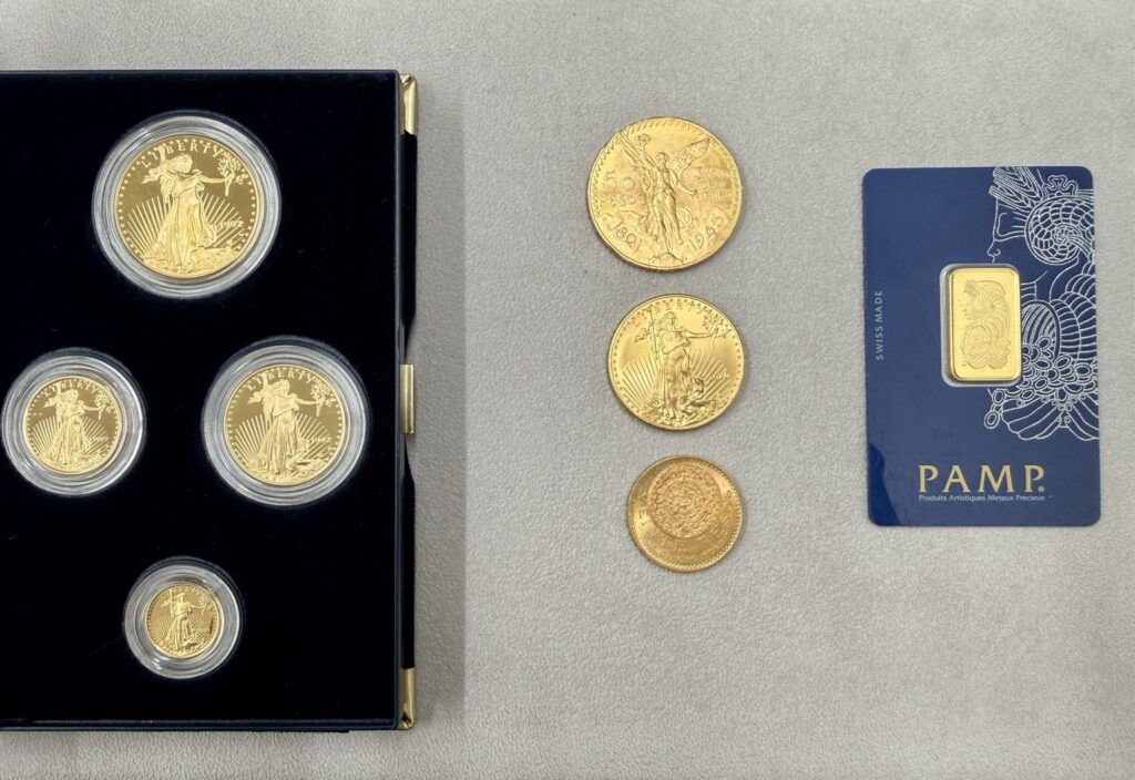 American Gold Eagle coins in a presentation case alongside loose gold coins and a PAMP Suisse gold bar