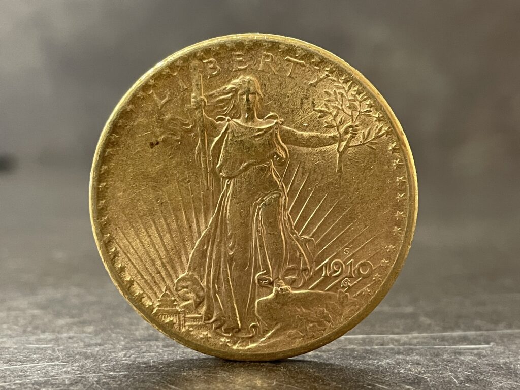 Saint-Gaudens Double Eagle gold coin showing Lady Liberty striding forward with torch and olive branch.