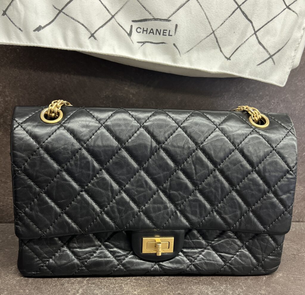 Chanel Reissue 2.55 black quilted lambskin flap handbag with aged gold-tone Mademoiselle clasp.